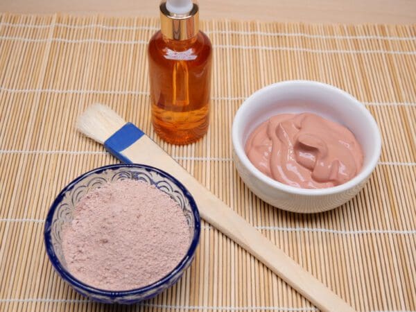 A bowl of clay next to some brush and a bottle.