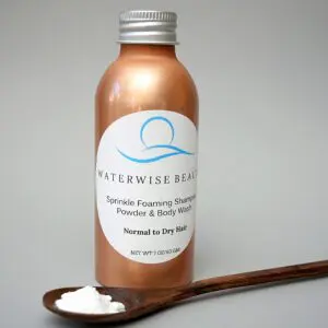 A bottle of lotion next to a wooden spoon.