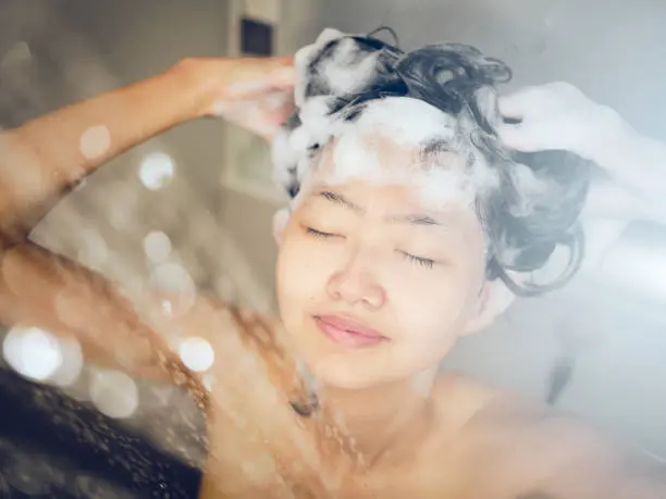 A woman is washing her hair with sustainable and natural soap, embracing eco-friendly hair and skin care.