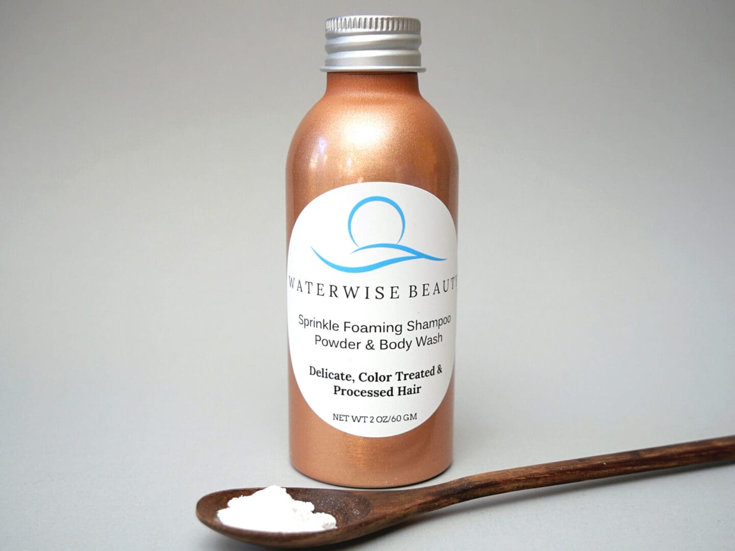 A bottle of Sprinkle Foaming Shampoo Powder & Body Wash for Delicate, Color Treated & Processed Hair next to a wooden spoon.