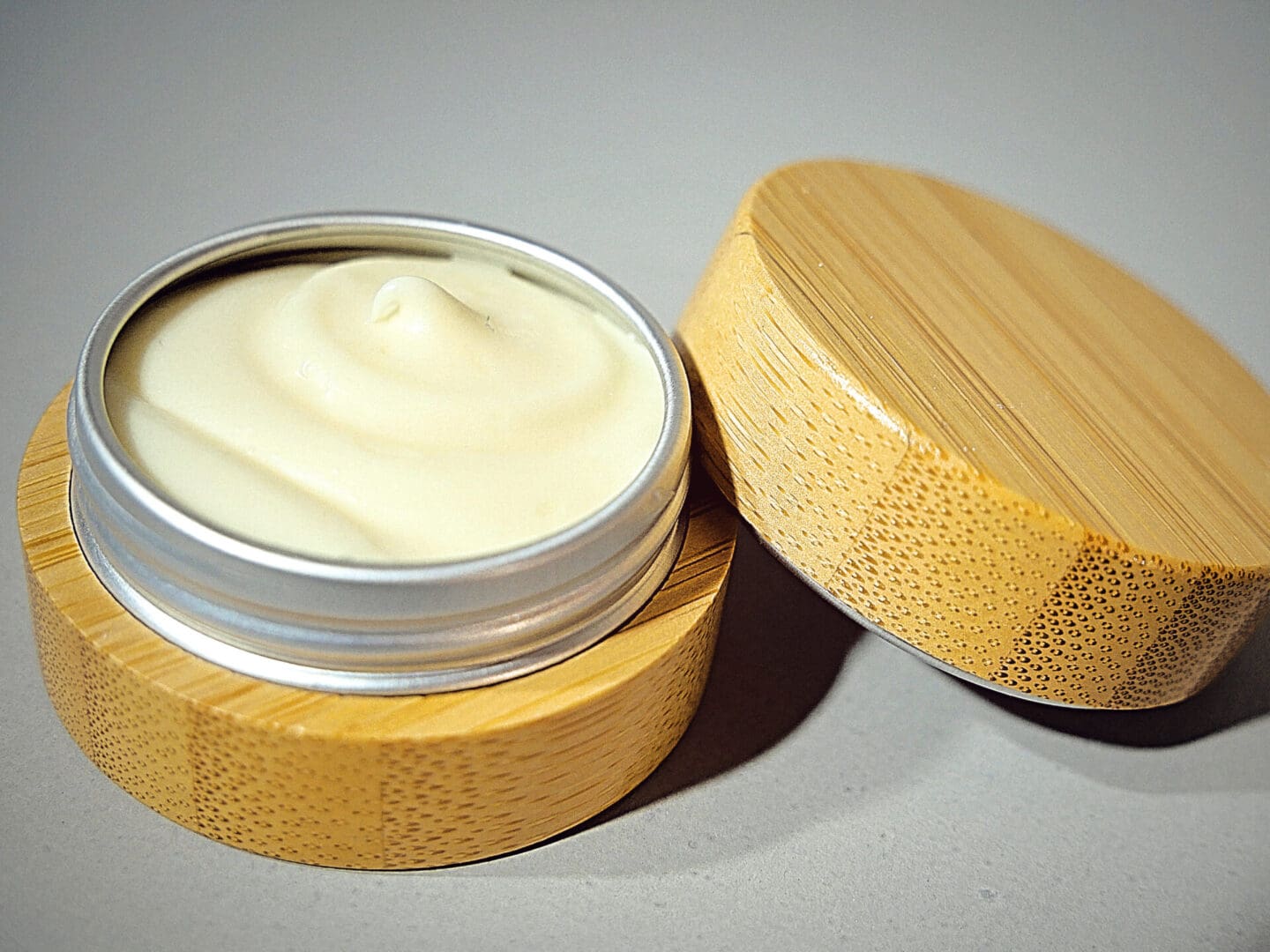 A wooden tin with NutrientRx Cuticle & Fingertip Butter in it.