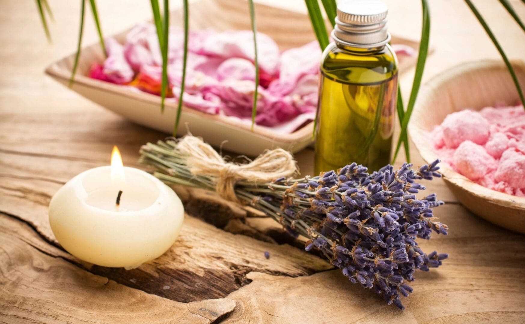Lavender essential oil and a candle on a wooden table.