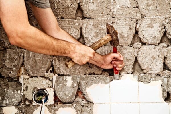 A person holding a hammer and nails on the ground.