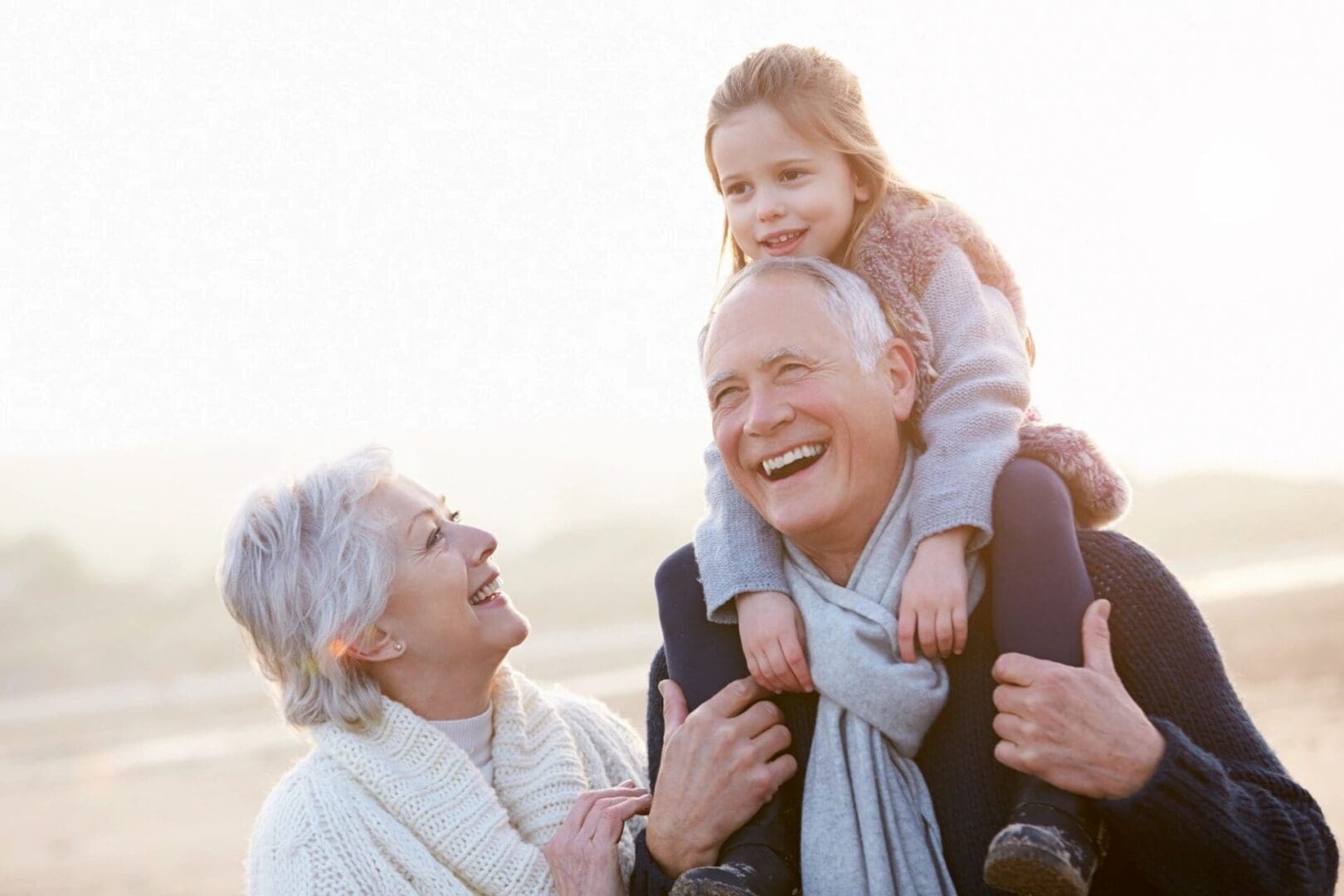 An older couple and a little girl are having fun on the beach.