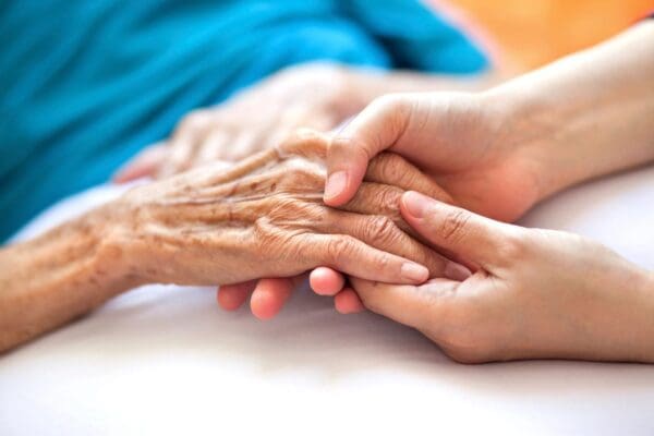 A person holding an elderly hand over another 's arm.