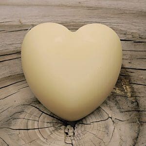 A white heart-shaped Kokum Butter Body Bar resting on a smooth piece of wood.