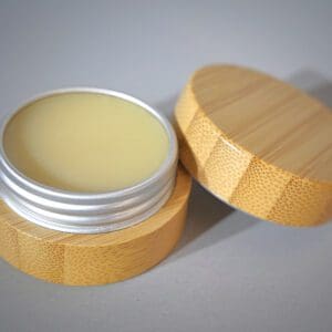A wooden container with the Hydrate & Restore Lip Balm in it.
