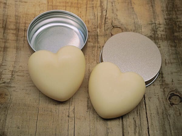 Two heart shaped soaps sitting next to a tin.