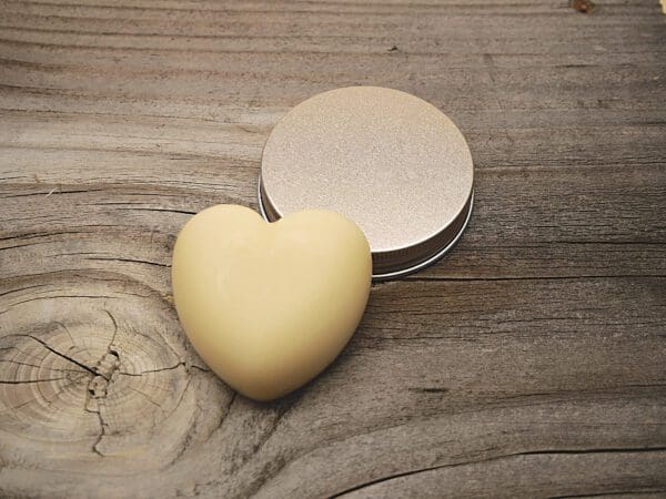 A heart shaped soap next to a tin of lotion.