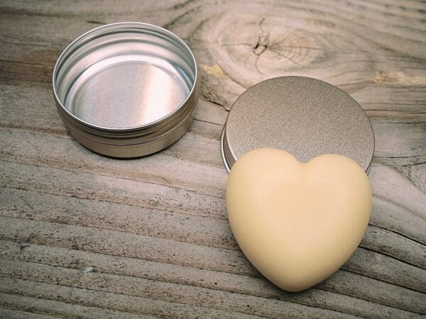 A heart shaped soap next to a tin of lotion.