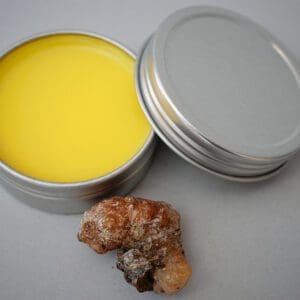 A tin of yellow wax next to a piece of rock.