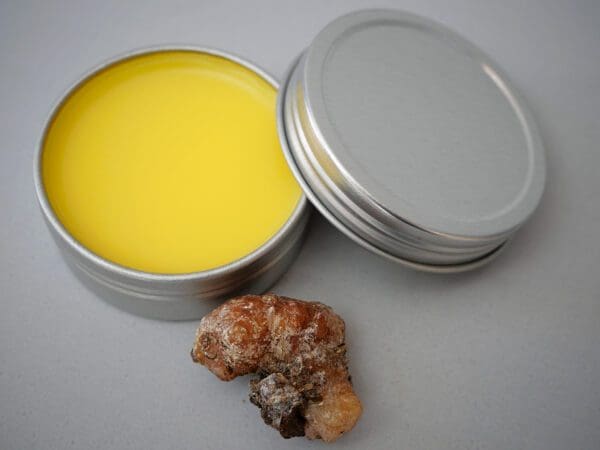 A tin of yellow wax next to a piece of rock.