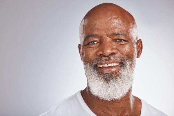 A man with white beard and smiling.