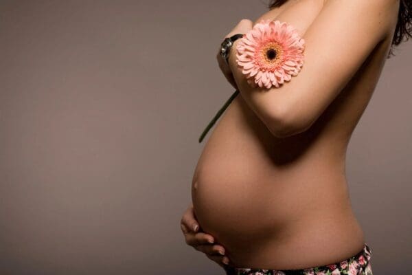 A pregnant woman holding a flower in her hand.